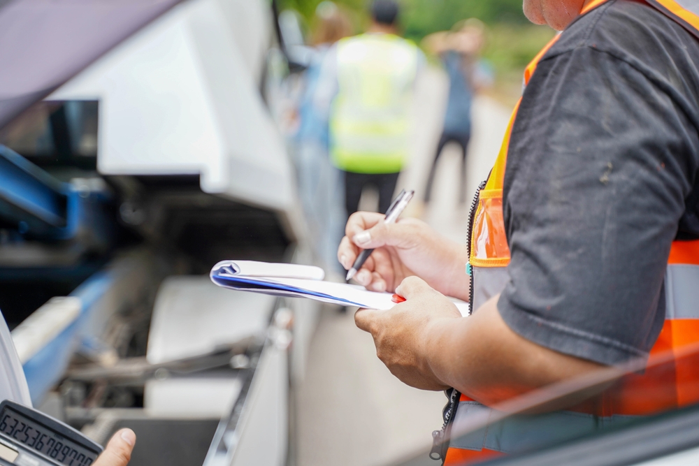 Investigator documenting damage and filing paperwork for insurance claims after a truck accident on a busy roadway.  