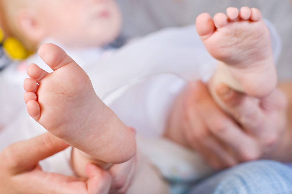 Parent holding baby’s feet, symbolizing the emotional impact of birth injuries and the need to prove medical negligence in infant care.