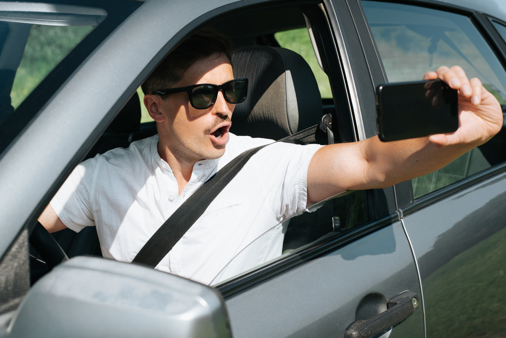 The photo shows a driver filming themselves while behind the wheel, highlighting a common scenario that raises the question: Can You File an Auto Accident Claim If the Other Driver Was Filming a TikTok While Driving?