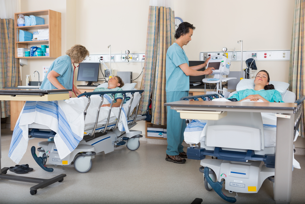 Two patients in hospital beds receiving care from medical staff, illustrating risks of post-surgical malpractice in recovery.