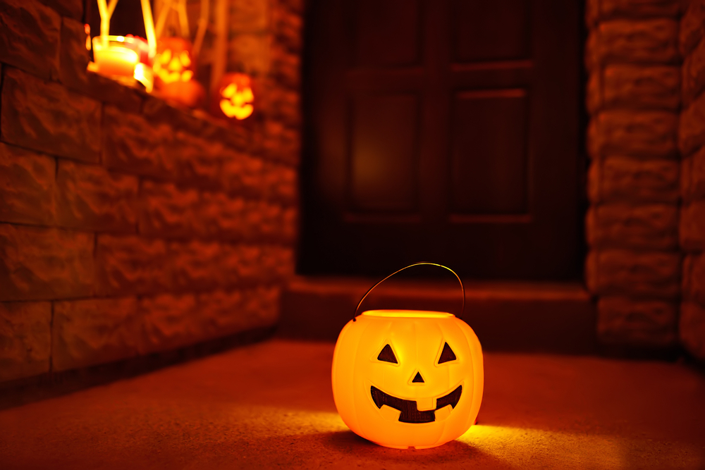 Halloween pumpkin bucket glowing on a porch, symbolizing Halloween night safety and the risk of car accidents in New Jersey.