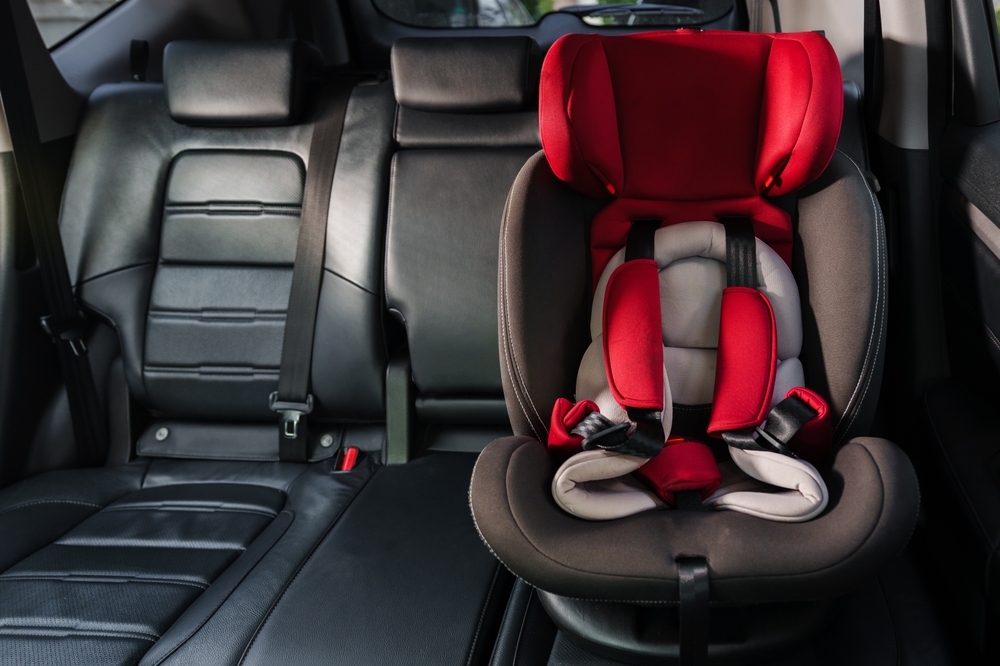 Red child safety seat in the back of a car, illustrating the risks of a defective car seat in New Jersey product liability cases.