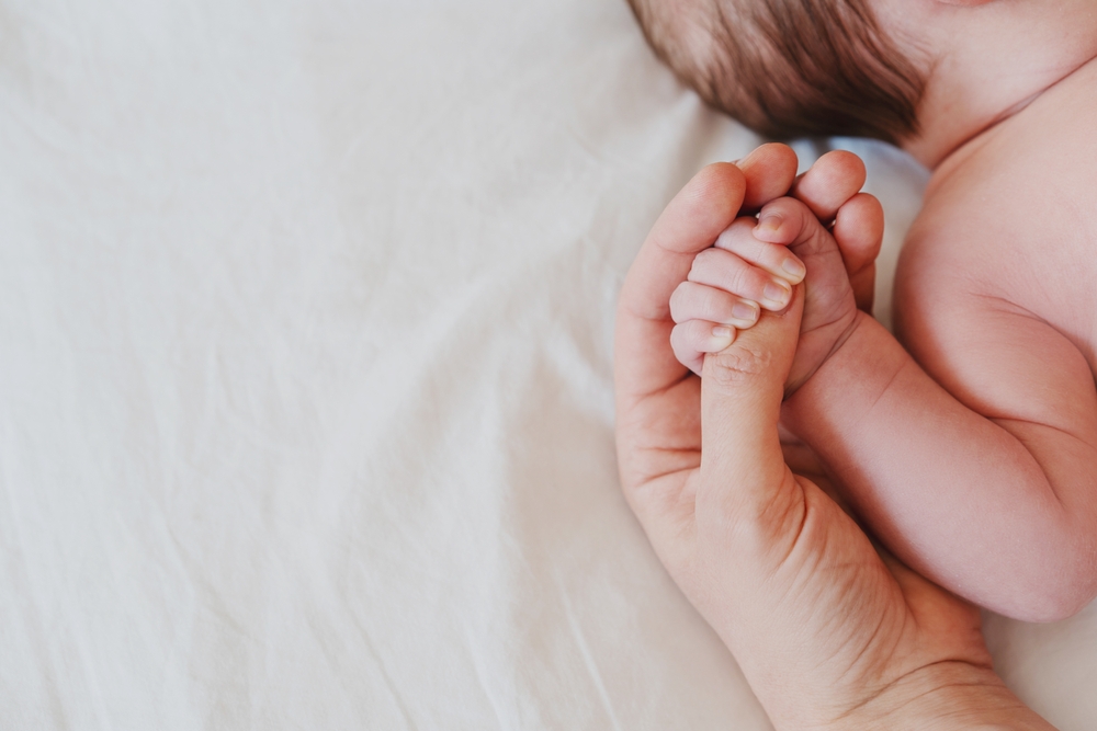 Newborn baby holding a parent’s finger, symbolizing care, protection, and awareness of possible birth injury signs.