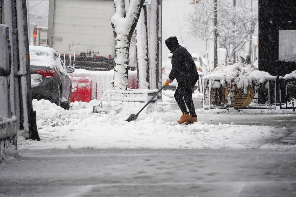 New Jersey business slip and fall risk as a person shovels snow and clears ice on an icy sidewalk outside a storefront.