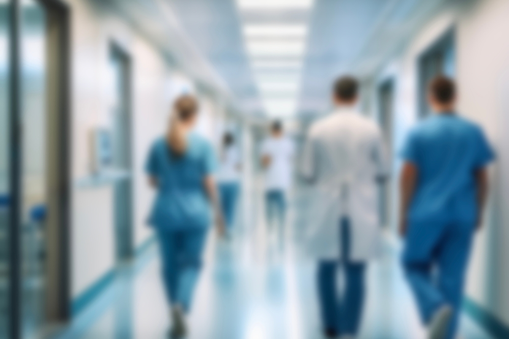 A blurred perspective of medical professionals in scrubs and white coats walking through a busy  hospital hallway during a shift surge.
