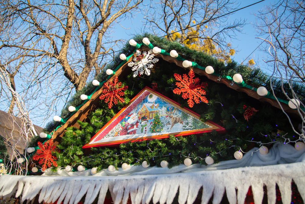 Close-up of a festive Christmas market stall roof in New Jersey, decorated with greenery and lights.