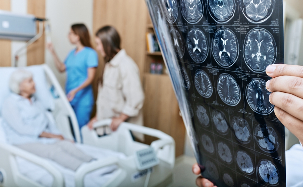 Doctor reviewing brain scans while patient receives hospital care after suspected stroke