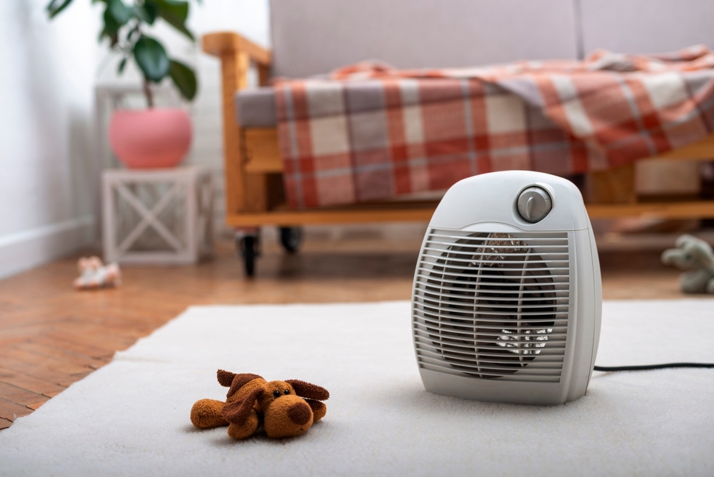 Portable space heater on bedroom floor showing potential burn and fire hazard from defective heating products in homes
