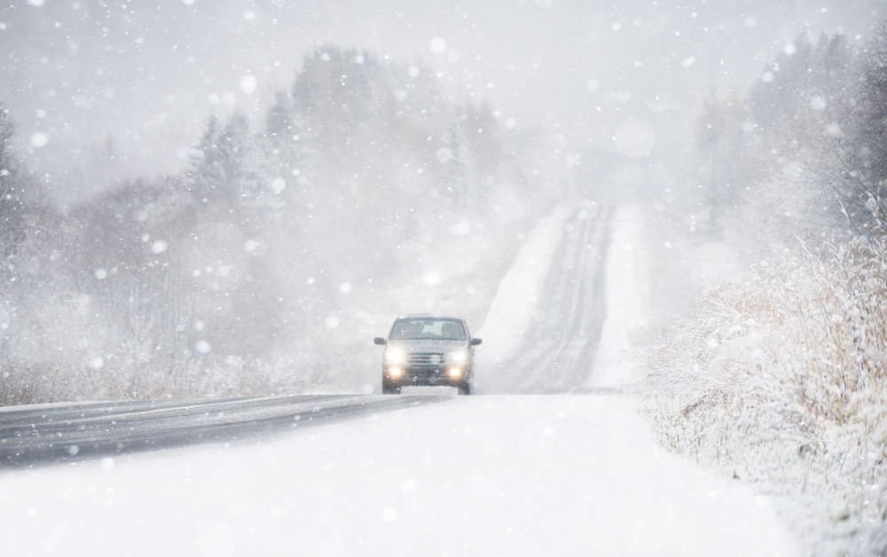 Car driving on a snowy rural road during a New Jersey blizzard with falling snow and low visibility