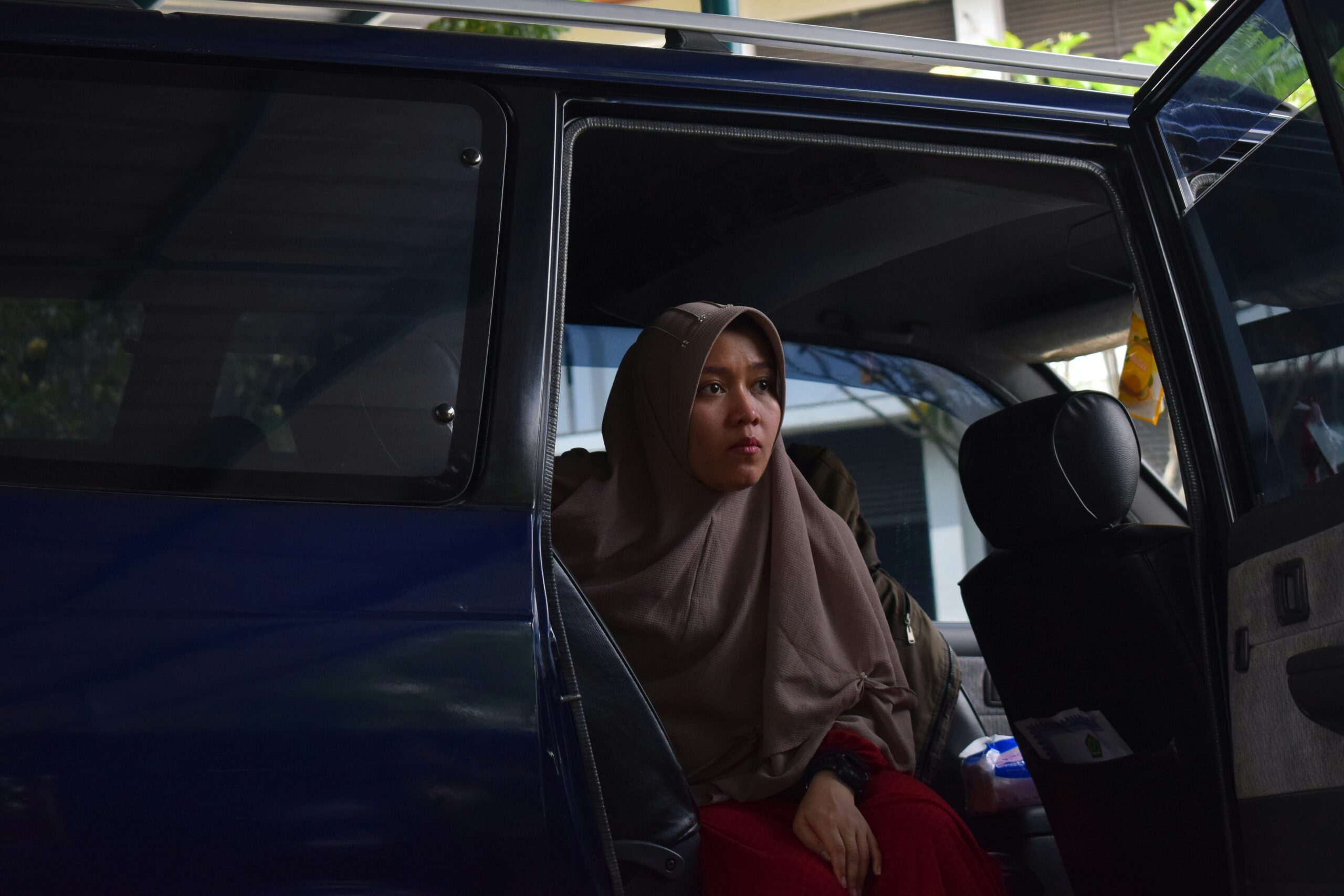 Woman sitting in a vehicle looking cautious, representing rideshare safety concerns and awareness of potential risks