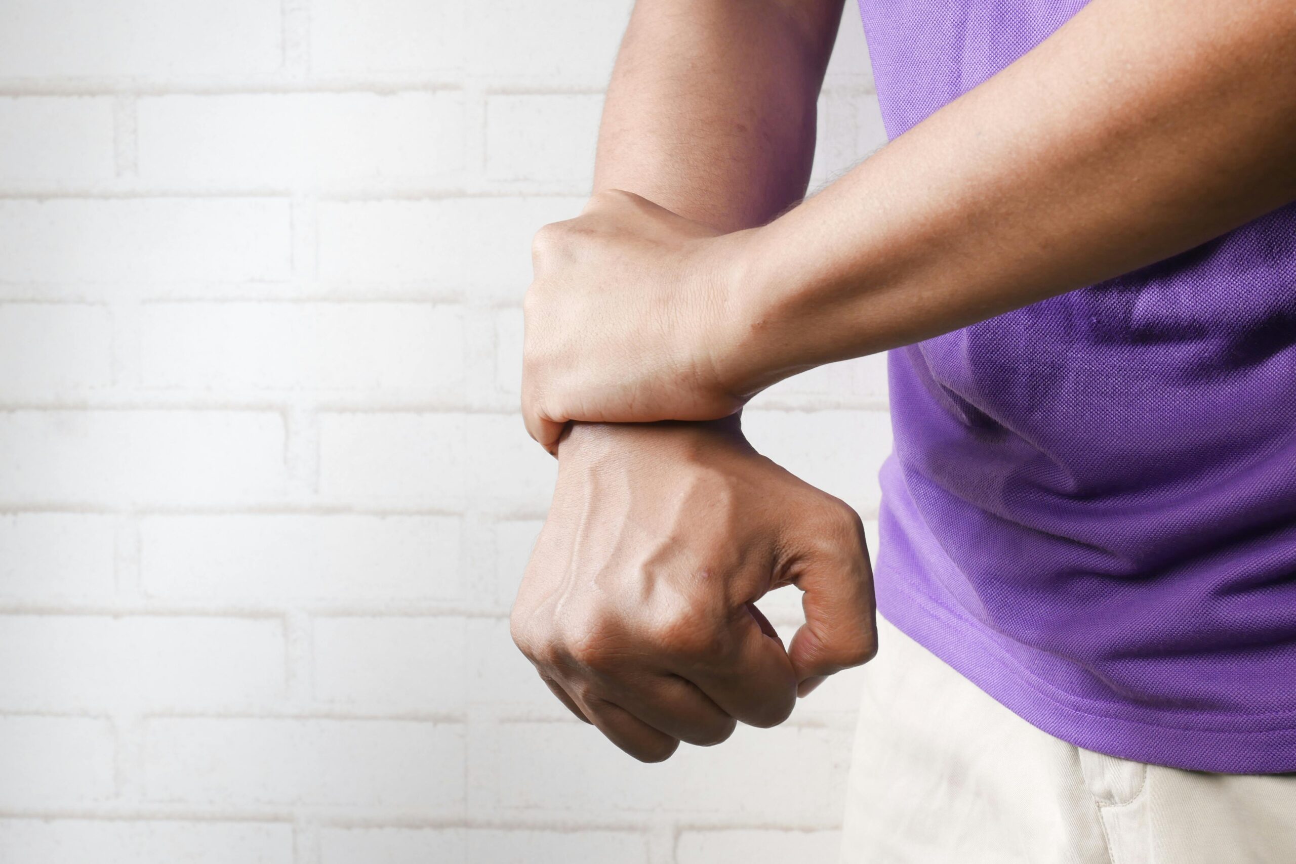 Person holding wrist in pain, representing chronic joint pain from work and repetitive stress injury claims in New Jersey.