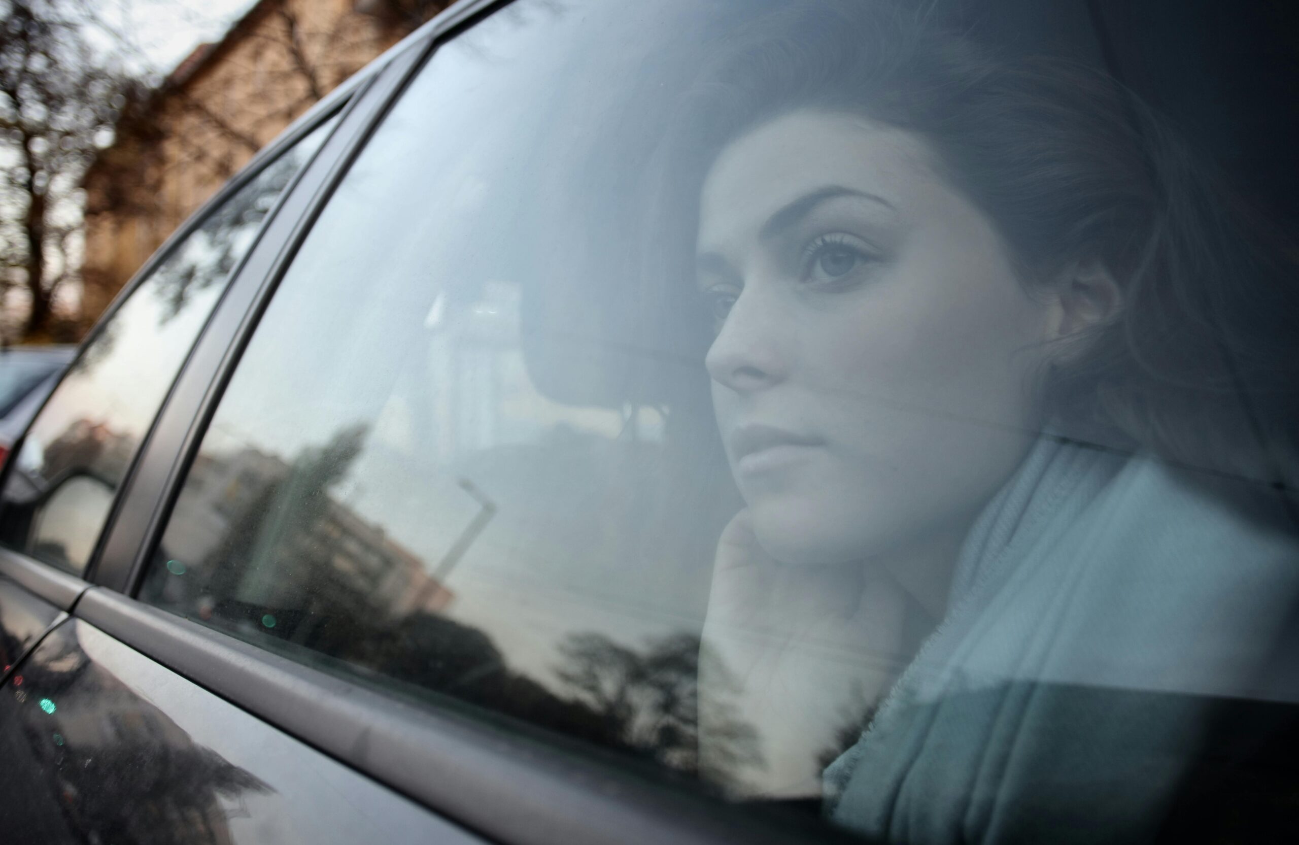 Woman sitting alone in the back seat of a car, representing Uber sexual assault liability and passenger safety concerns.