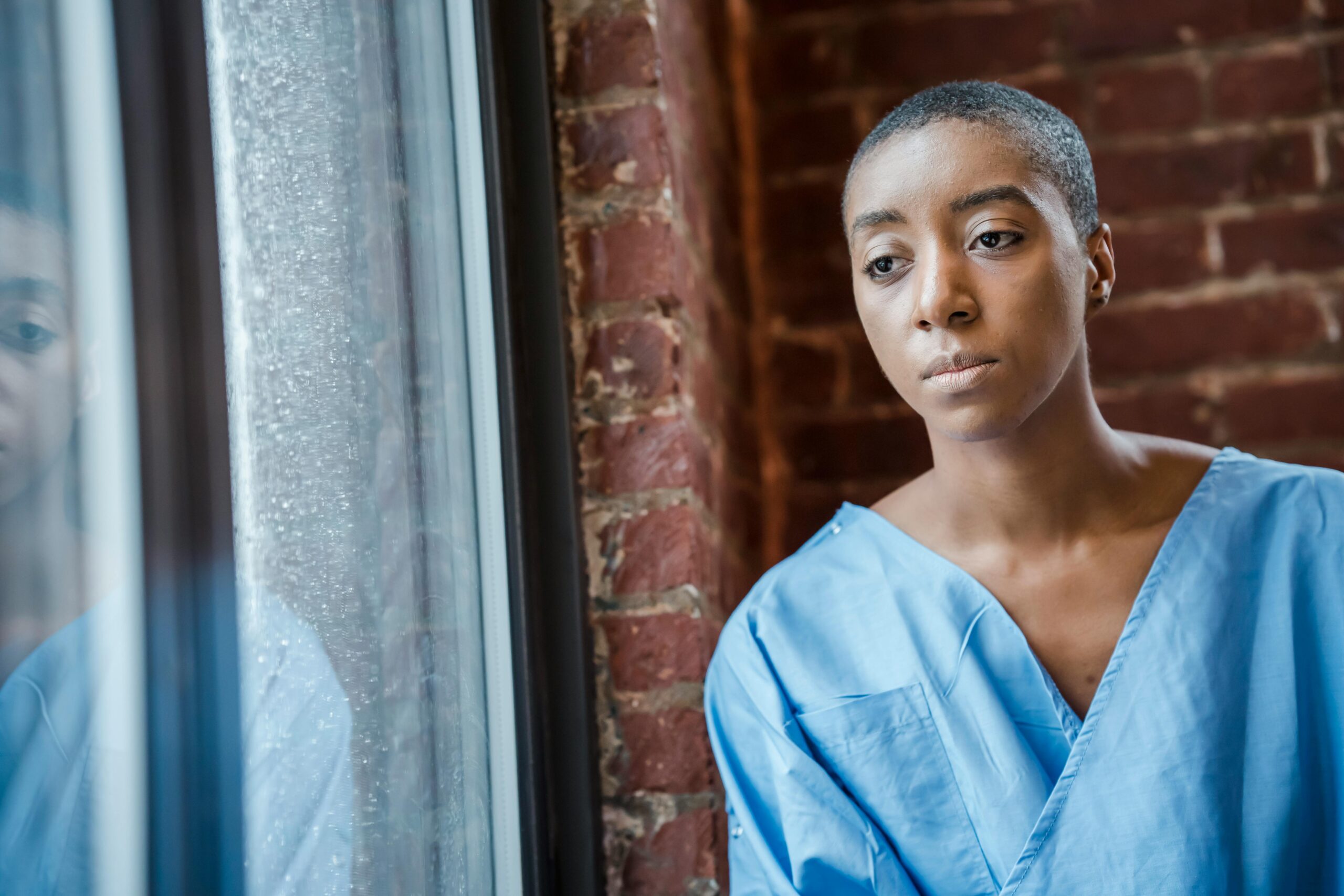 Patient in hospital gown looking out window, symbolizing the impact of oncology care errors in New Jersey cancer treatment