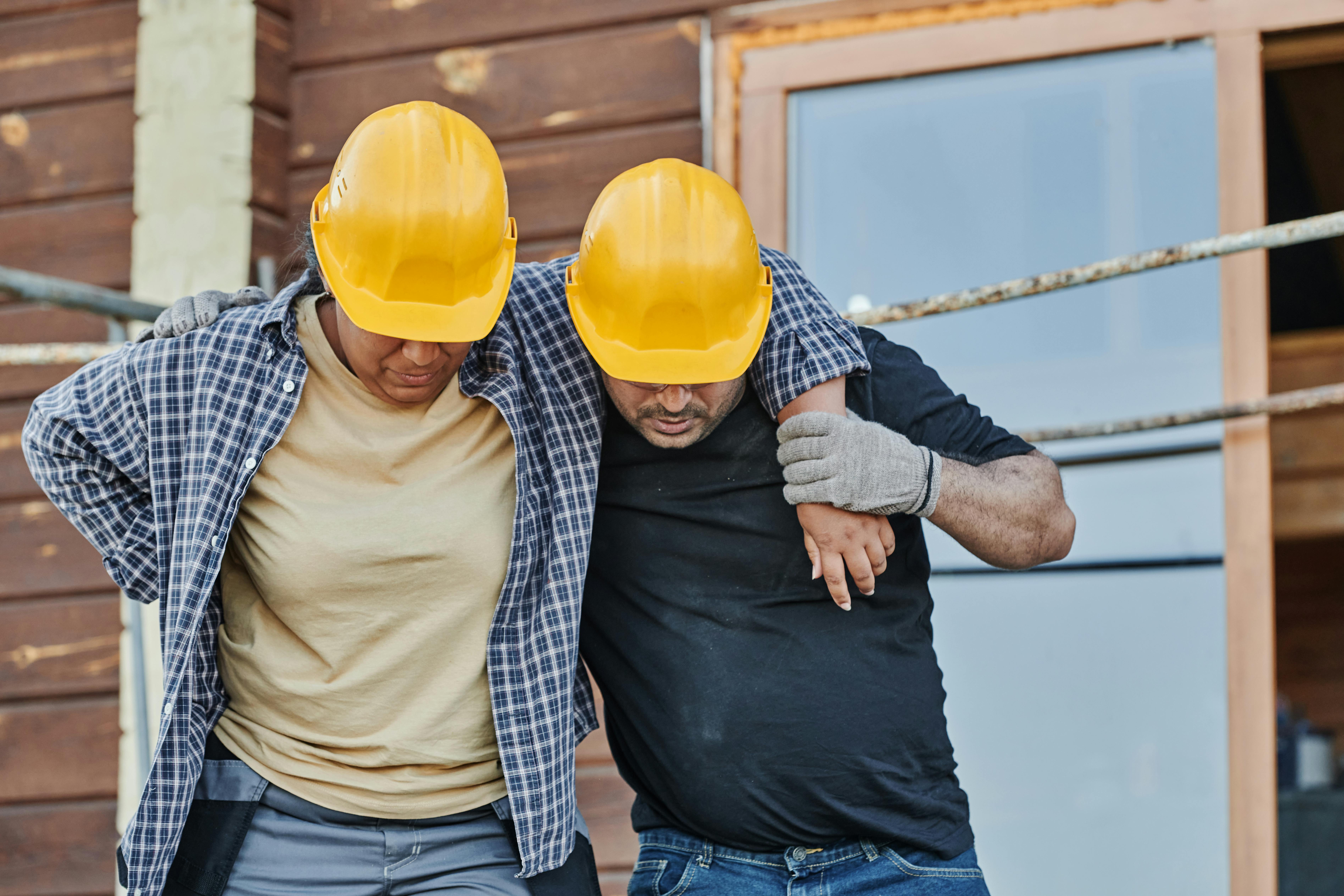Injured construction worker being helped by a coworker after unsafe work conditions led to a New Jersey workplace accident.