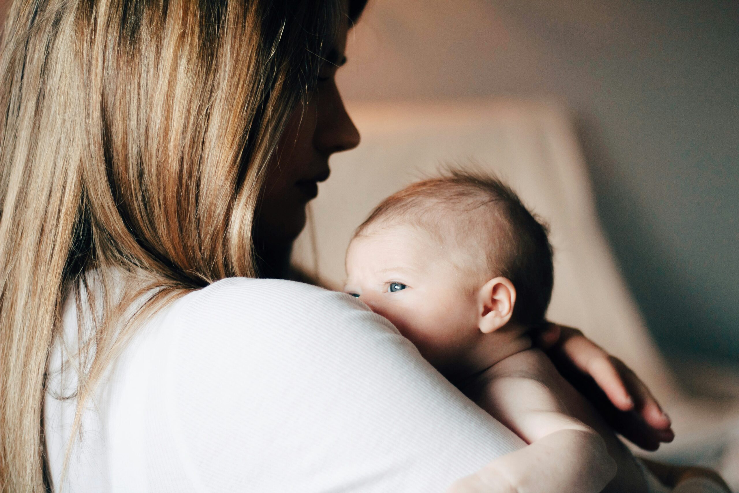 Mother holding her newborn against her shoulder, illustrative image representing early bonding and the risks of a missed genetic diagnosis at birth.