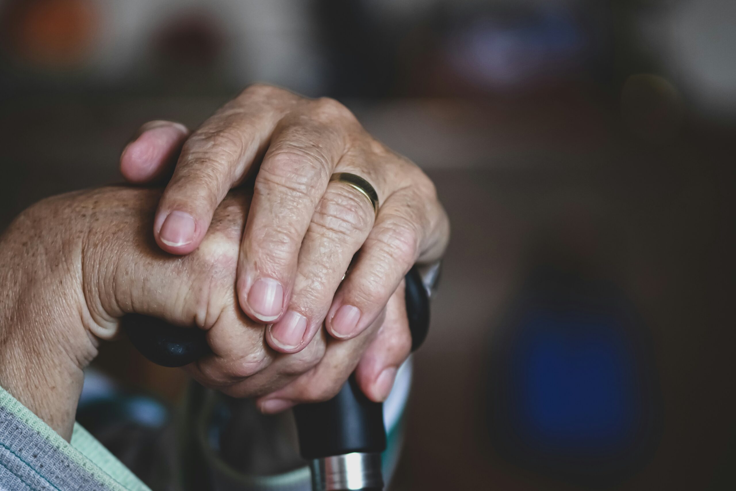 Elderly hands clasped together on a cane, illustrative image representing memory loss and the impact of a missed or delayed Alzheimer's diagnosis.