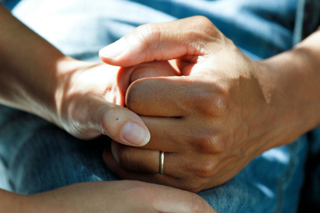 Two people clasping hands for comfort, symbolizing support for Keyport cancer cluster families living near the Aeromarine landfill.